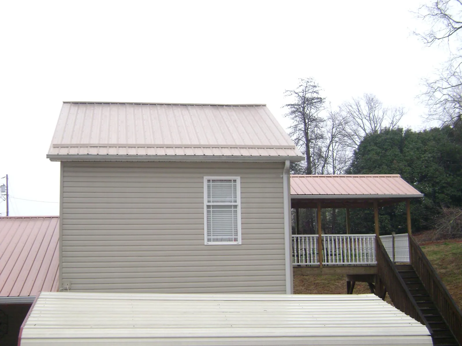 Tan metal roofs on a two story addition and attached porch, from a Roof Replacement job in Dover